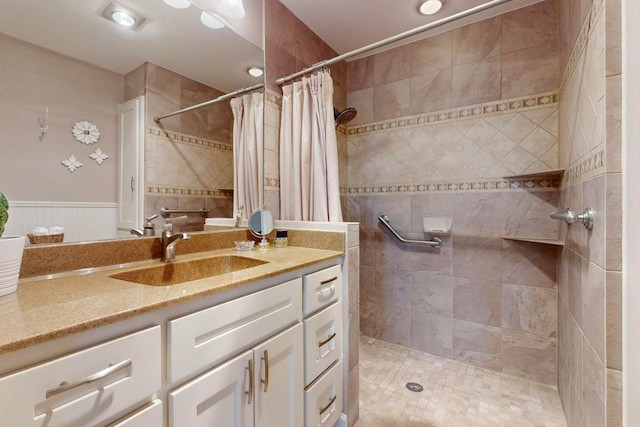 full bathroom with vanity, wainscoting, and tiled shower