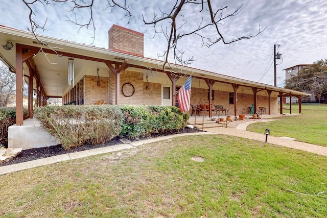 view of front facade featuring brick siding, a chimney, and a front lawn