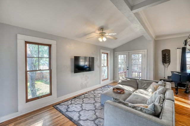 living room featuring lofted ceiling with beams, wood finished floors, a ceiling fan, baseboards, and french doors