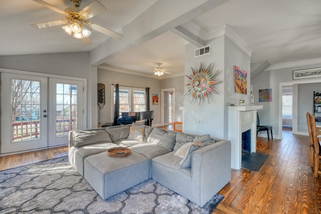 living area featuring lofted ceiling, a fireplace with flush hearth, french doors, ornamental molding, and wood-type flooring