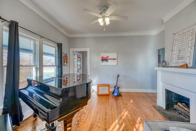 living area with a fireplace, crown molding, baseboards, and wood finished floors