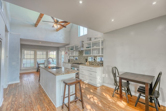 kitchen with wall chimney range hood, light wood-type flooring, and a sink