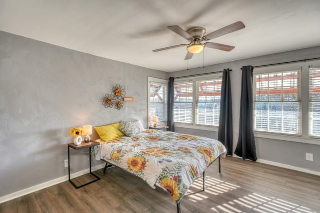 bedroom with multiple windows, baseboards, and wood finished floors