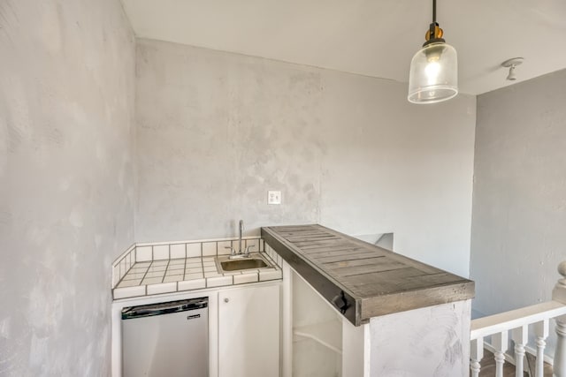 kitchen with hanging light fixtures, a sink, and tile counters