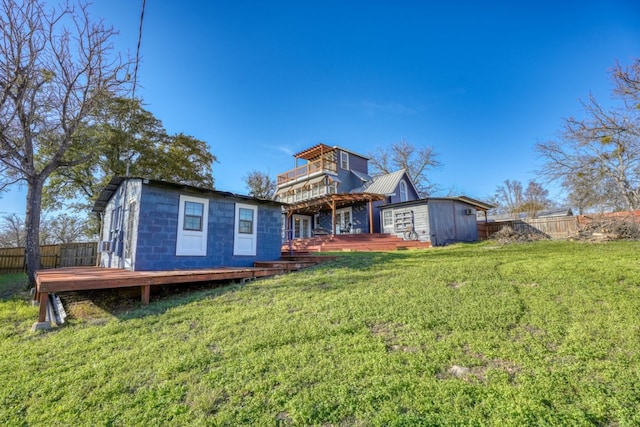 back of house featuring fence, metal roof, a lawn, and a wooden deck