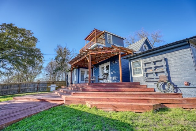 rear view of house with metal roof, fence, a deck, and french doors