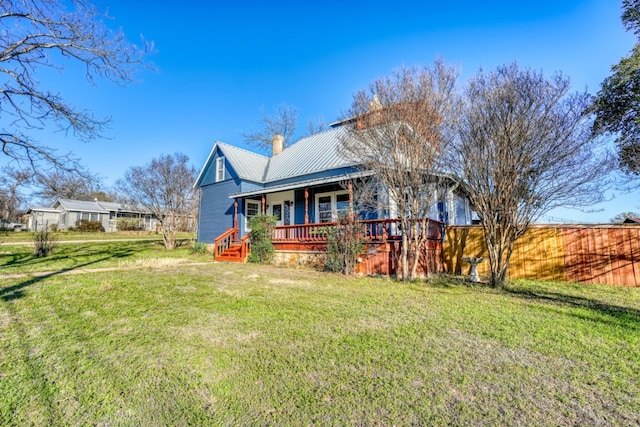 view of front of home with covered porch, metal roof, a chimney, and a front lawn