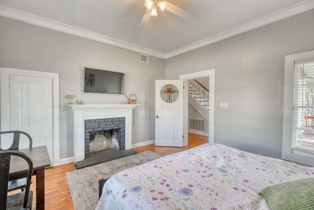 bedroom featuring crown molding, a fireplace, visible vents, and wood finished floors