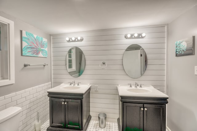 bathroom with toilet, two vanities, and a sink