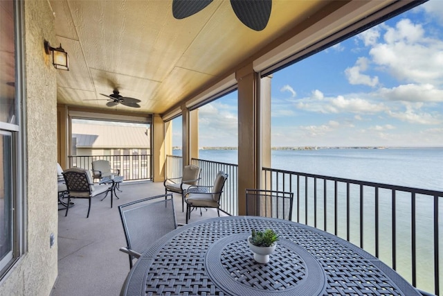 balcony featuring a ceiling fan, outdoor dining space, and a water view