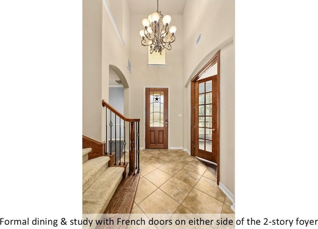 foyer entrance featuring a chandelier, stairway, visible vents, and baseboards