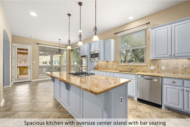 kitchen with stainless steel appliances, backsplash, a sink, and a center island