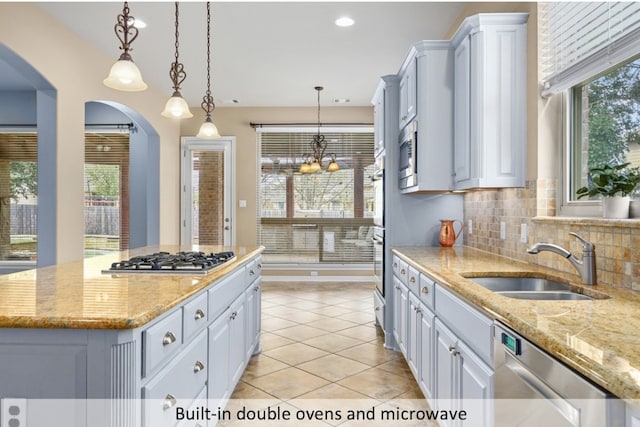 kitchen featuring light tile patterned flooring, a sink, appliances with stainless steel finishes, backsplash, and a wealth of natural light