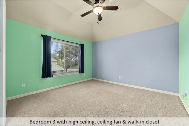 carpeted empty room featuring lofted ceiling, ceiling fan, and baseboards