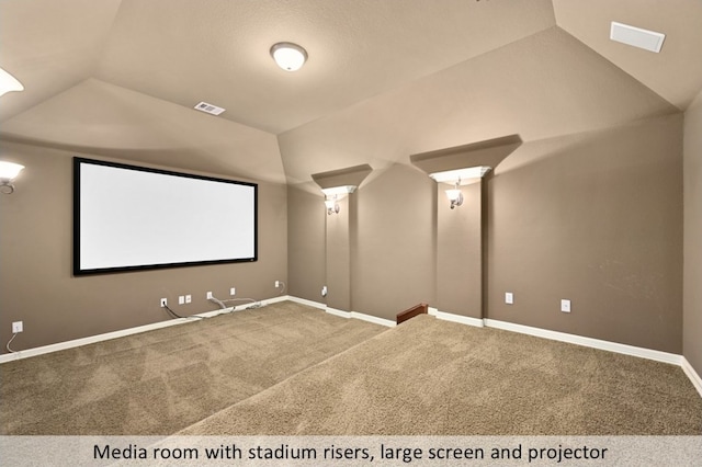 carpeted cinema room with baseboards, visible vents, and vaulted ceiling