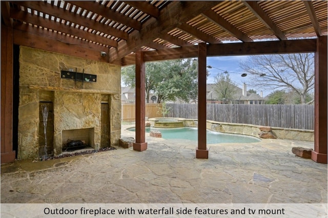 view of patio / terrace with an outdoor stone fireplace, a fenced backyard, and a pool with connected hot tub