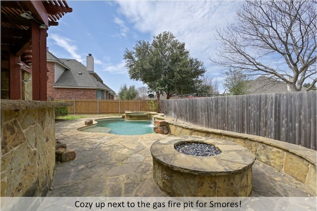 view of pool featuring a pool with connected hot tub, a fenced backyard, a patio, and a fire pit