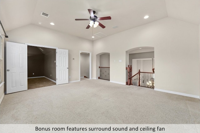 interior space featuring visible vents, arched walkways, carpet floors, and vaulted ceiling