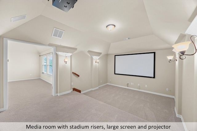 carpeted cinema room featuring baseboards, visible vents, and vaulted ceiling