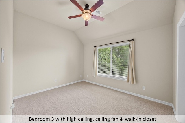 spare room featuring carpet, a ceiling fan, vaulted ceiling, and baseboards