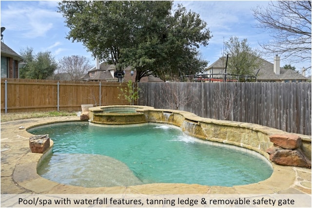 view of pool with a fenced backyard and a pool with connected hot tub