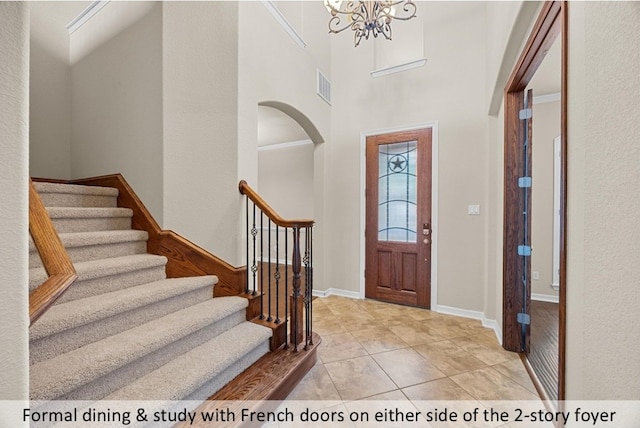 entryway featuring stairway, a chandelier, light tile patterned flooring, visible vents, and arched walkways