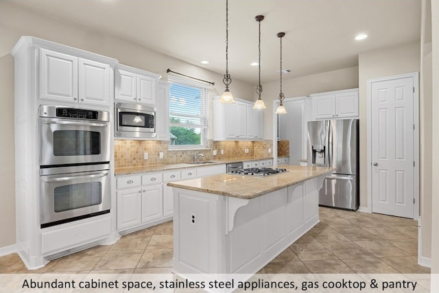 kitchen featuring tasteful backsplash, appliances with stainless steel finishes, a kitchen island, a sink, and white cabinetry