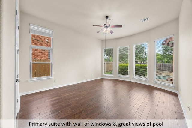 unfurnished room featuring a ceiling fan, visible vents, dark wood-style flooring, and plenty of natural light