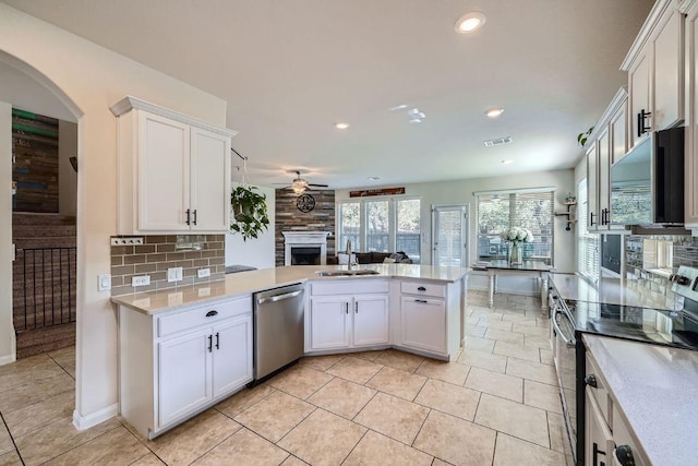 kitchen with a sink, tasteful backsplash, stainless steel appliances, a peninsula, and ceiling fan