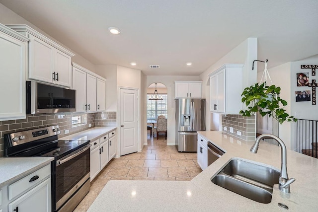 kitchen with white cabinetry, arched walkways, appliances with stainless steel finishes, and a sink