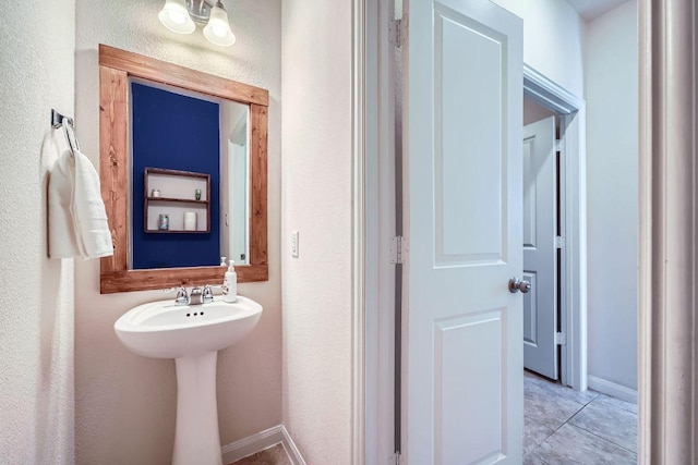 bathroom with tile patterned floors, a textured wall, and baseboards