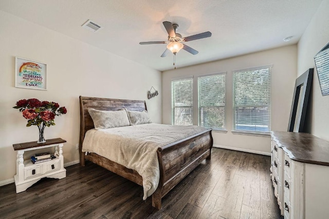 bedroom with visible vents, baseboards, dark wood finished floors, and a ceiling fan