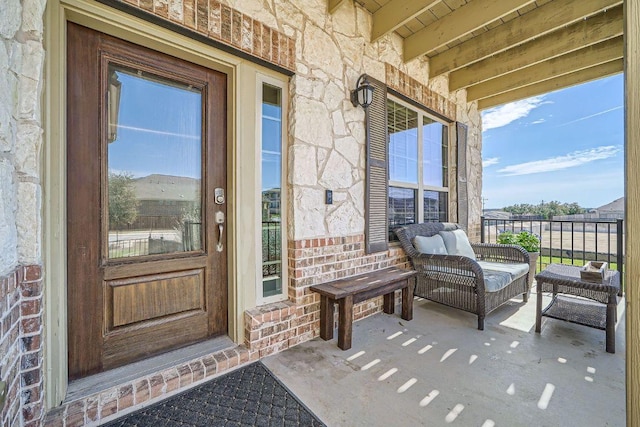 view of exterior entry with covered porch, brick siding, and stone siding