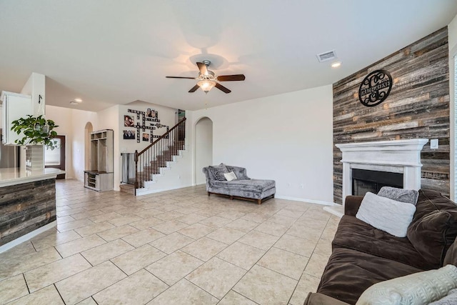 165 Crescent Heights Dr, Georgetown, TX 78628 - living room featuring arched walkways, stairs, a ceiling fan, a fireplace with raised hearth, and light tile patterned floors