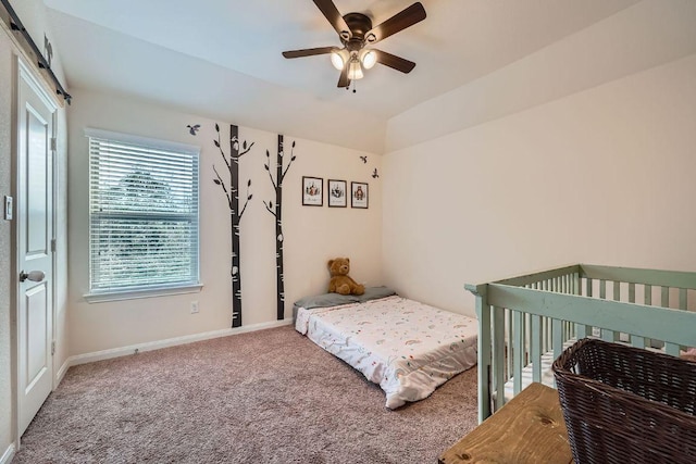 bedroom with baseboards, carpet, a barn door, vaulted ceiling, and a ceiling fan