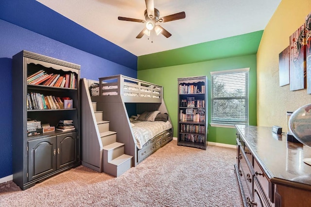 bedroom with baseboards, light colored carpet, a ceiling fan, and a textured wall