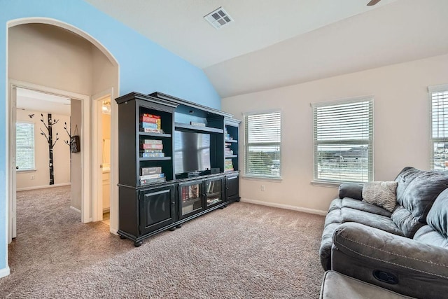 living area featuring visible vents, lofted ceiling, arched walkways, baseboards, and light colored carpet