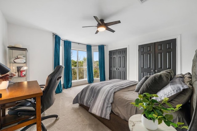 bedroom featuring light carpet, two closets, and a ceiling fan