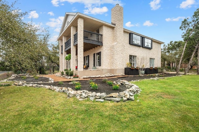 rear view of property with a lawn, a chimney, and a balcony