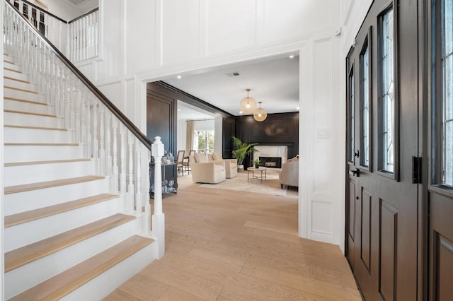 foyer featuring stairway, light wood finished floors, visible vents, and a decorative wall