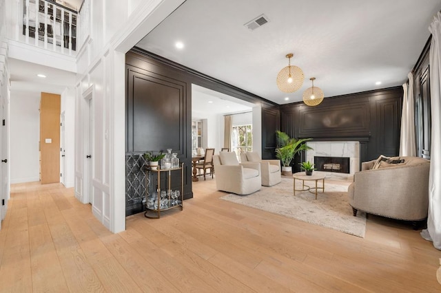 living area featuring light wood-style flooring, a decorative wall, a fireplace, and visible vents