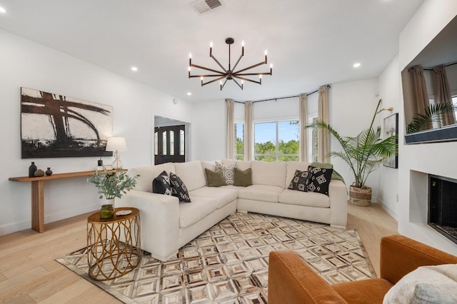 living room featuring a glass covered fireplace, recessed lighting, wood finished floors, and visible vents