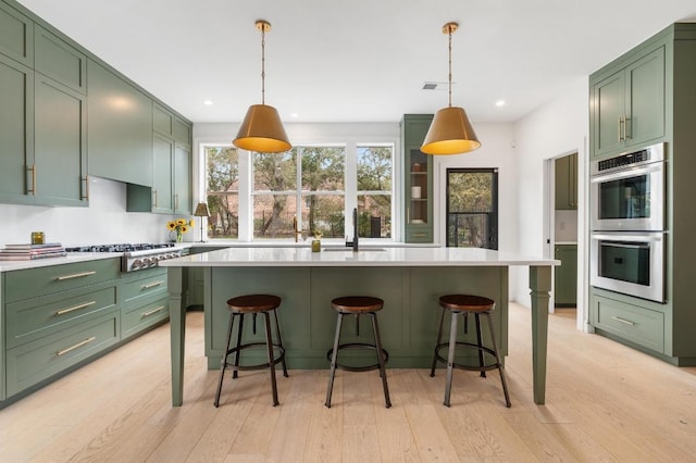 kitchen with a sink, appliances with stainless steel finishes, light countertops, and green cabinetry