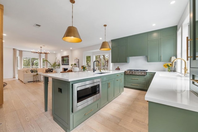 kitchen featuring green cabinets, visible vents, appliances with stainless steel finishes, and a sink