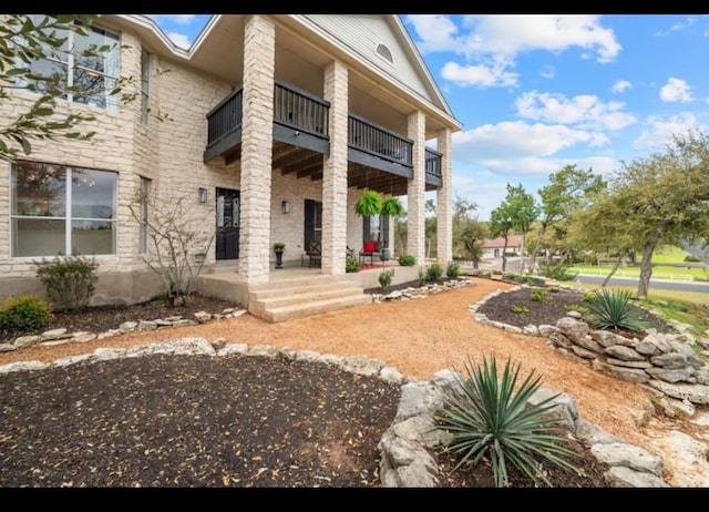 rear view of house featuring a balcony, a patio area, and stone siding