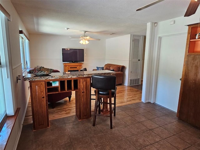 dining room featuring dark tile patterned floors, a textured ceiling, and a ceiling fan