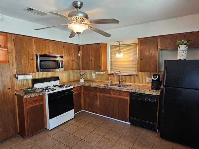 kitchen featuring brown cabinets, visible vents, a sink, dark tile patterned flooring, and black appliances