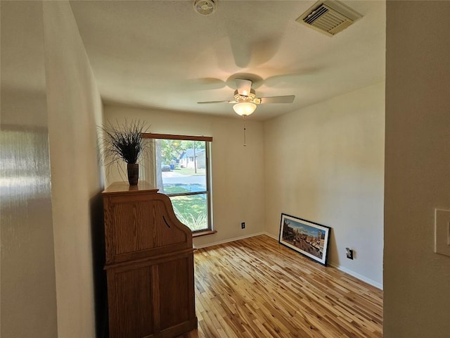 interior space featuring light wood-type flooring, visible vents, ceiling fan, and baseboards