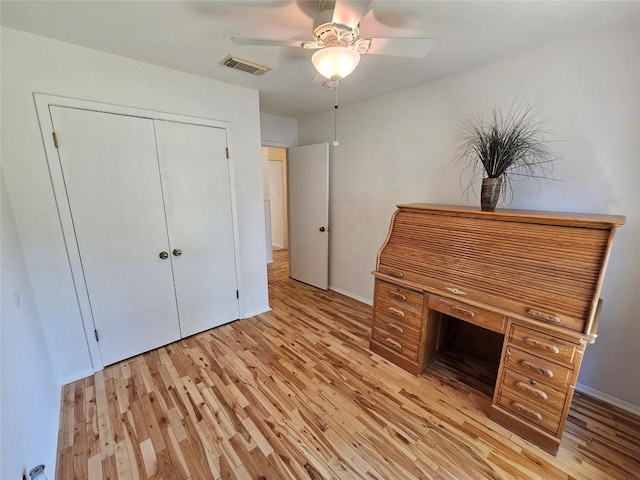 interior space with a ceiling fan, visible vents, light wood-style flooring, and baseboards