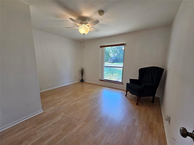 unfurnished room featuring light wood-style flooring, a textured ceiling, baseboards, and a ceiling fan